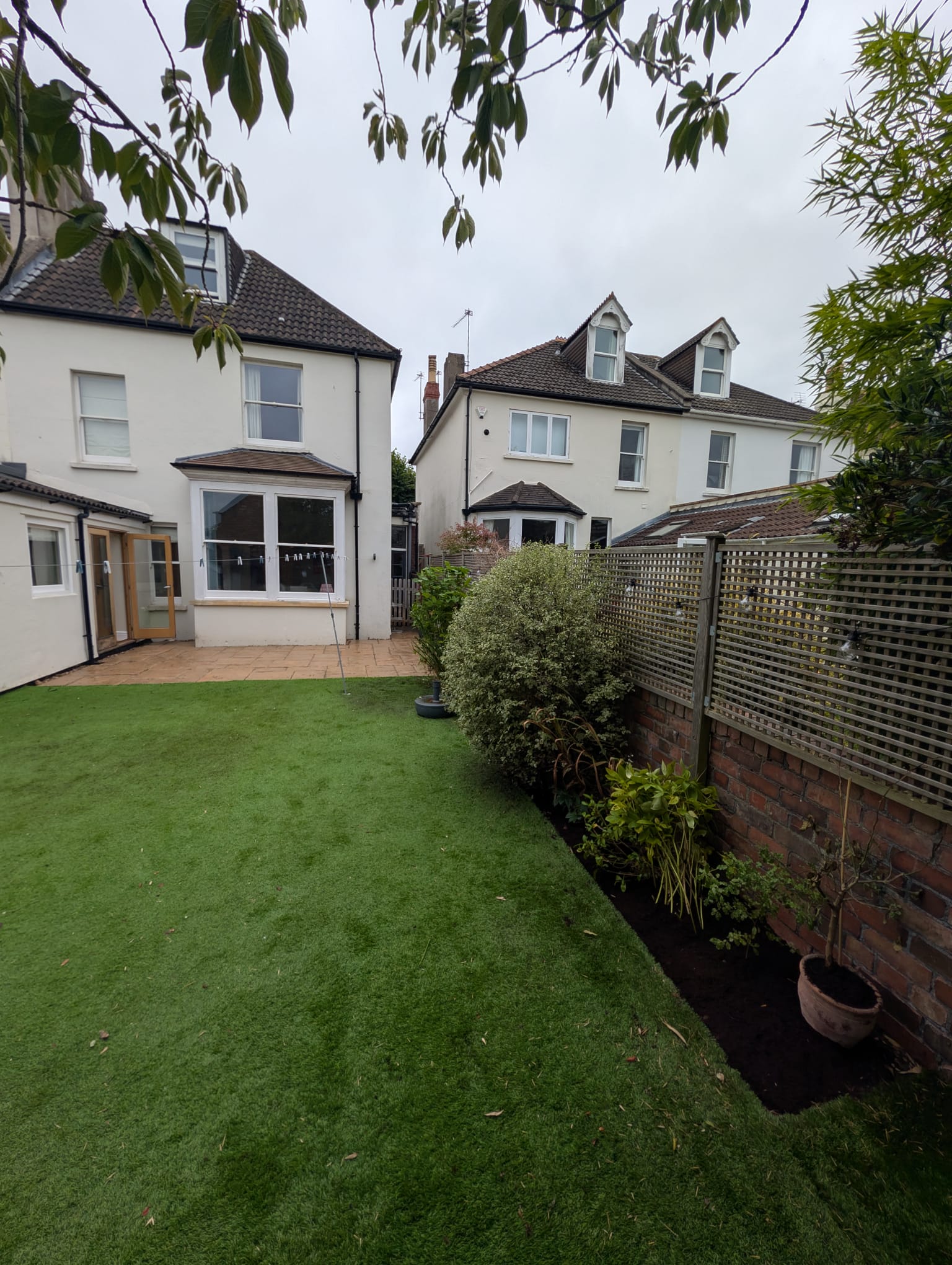 After: cut-back planting and a defined border beside a cleared artificial lawn