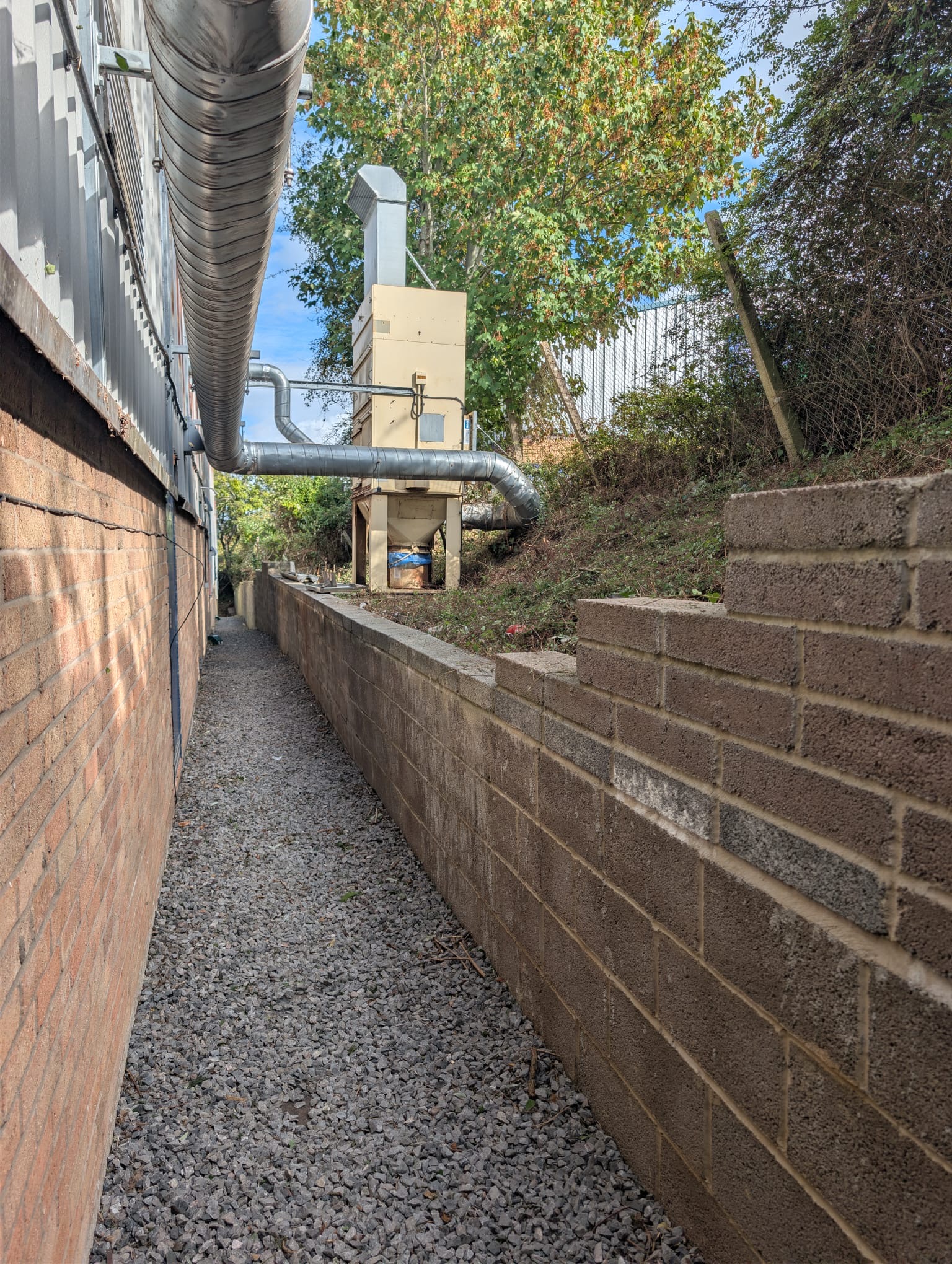 After: vegetation cleared beside the commercial premises, with the gravel access route visible