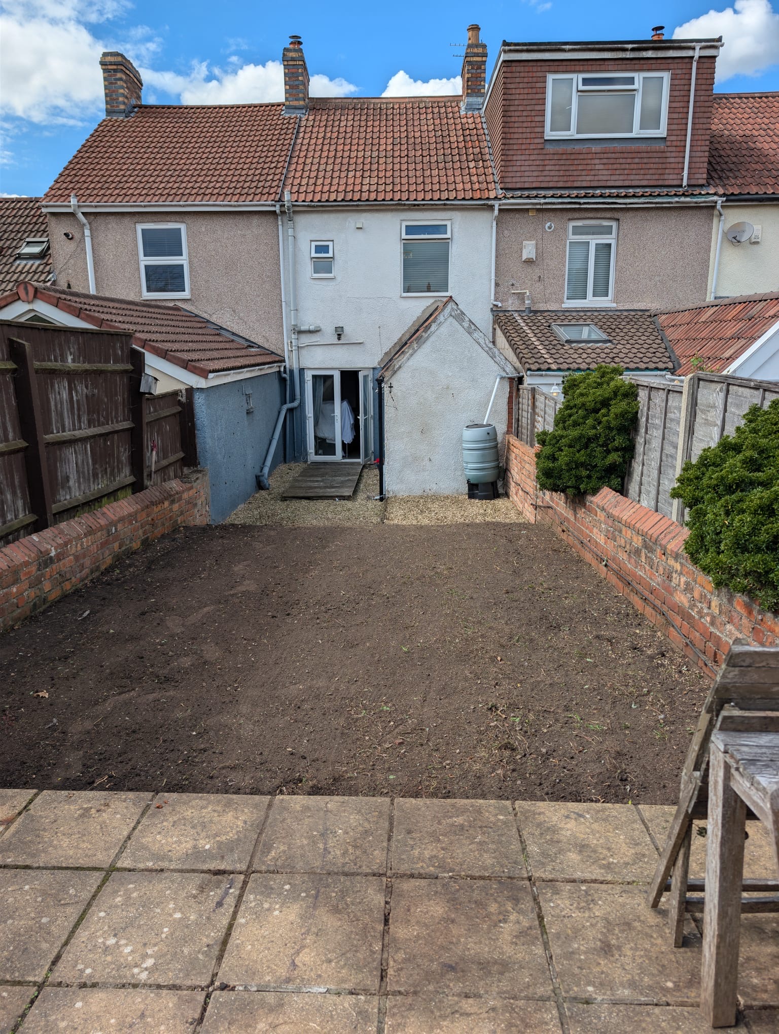 After: the same garden cleared, with bare soil and tidy gravel beside the house