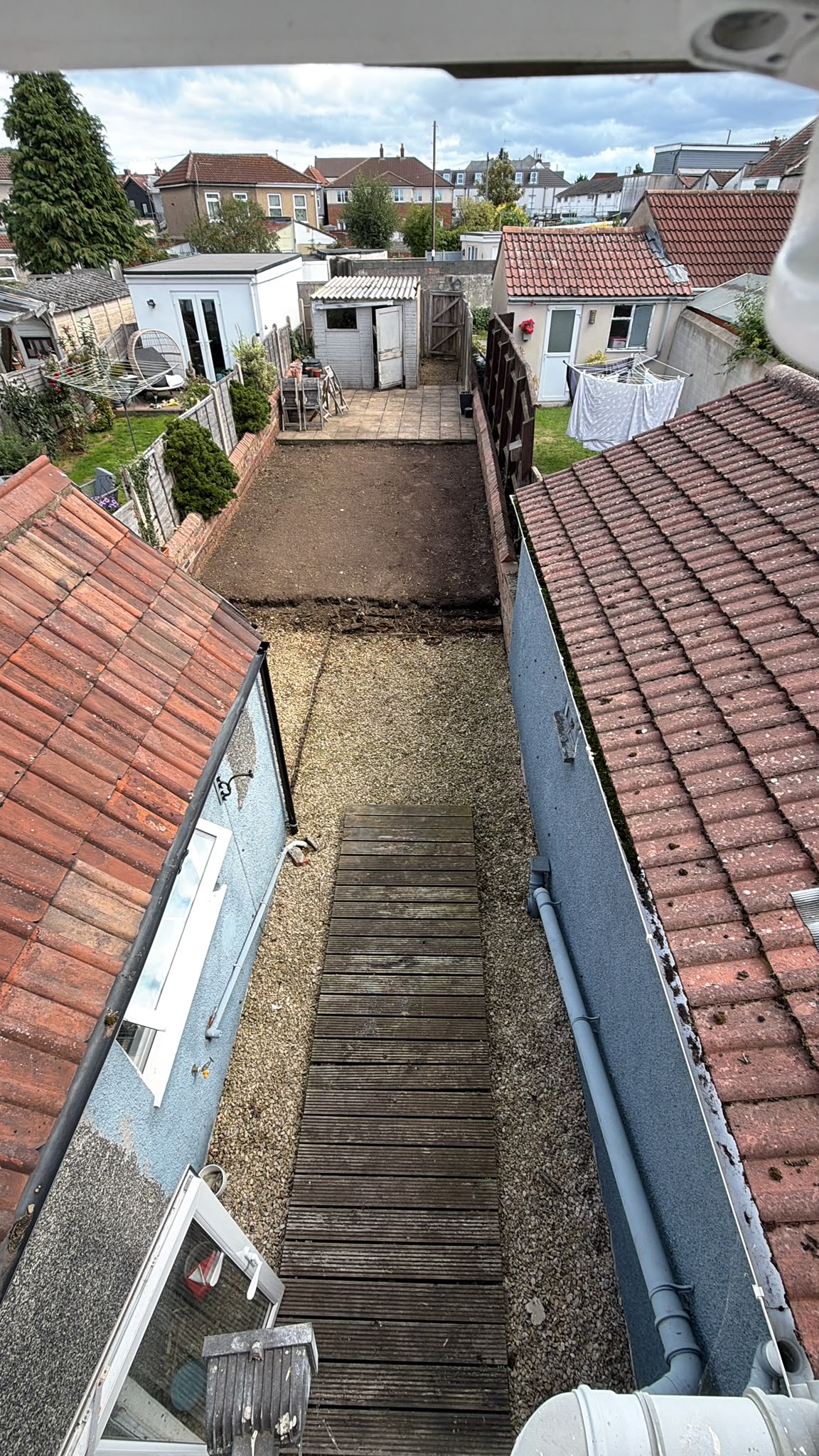 After: the same view with a cleared garden, visible gravel and wooden walkway
